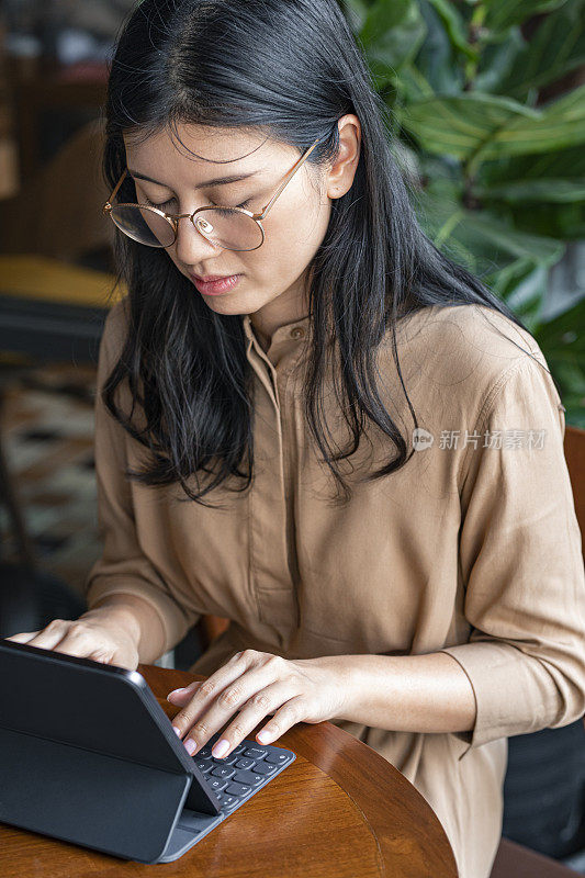 亚洲女性/大学生使用数字平板电脑在咖啡馆远程学习